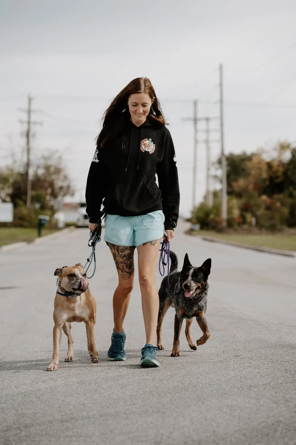 A trainer walking two dogs on a loose leash